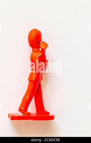 Airfix 1960 HO/00 scale figure from the Guards Band series. Toy Guardsman marching, playing the French horn, modelled in red plastic. White background. Stock Photo