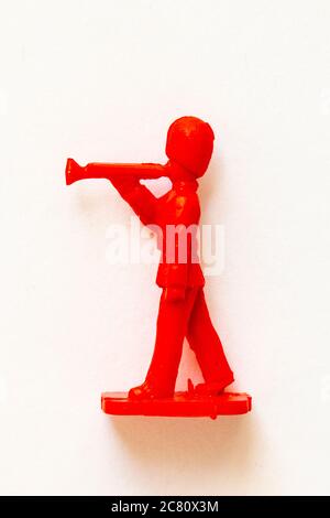 Airfix 1960 HO/00 scale figure from the Guards Band series. Toy Guardsman marching and playing the trumpet, modelled in red plastic. White background. Stock Photo