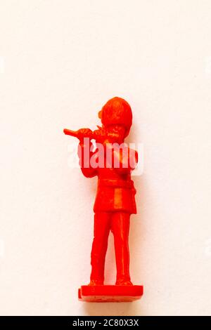 Airfix 1960 HO/00 scale figure from the Guards Band series. Toy Guardsman marching and playing the fife, modelled in red plastic. White background. Stock Photo
