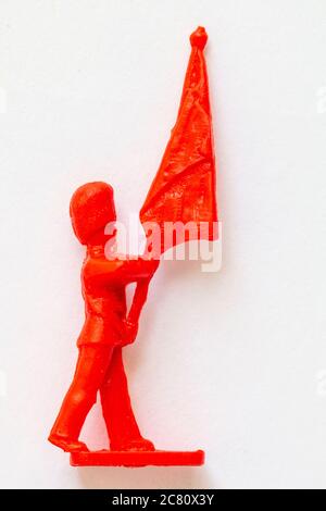Airfix 1960 HO/00 scale figure from the Guard series. Red plastic toy Guardsman standard bearer marching and holding the colours. White background. Stock Photo