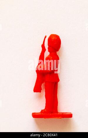 Airfix 1960 HO/00 scale figure from the Guard series. Red plastic toy Guardsman standing to attention with rifle. Side view. White background. Stock Photo