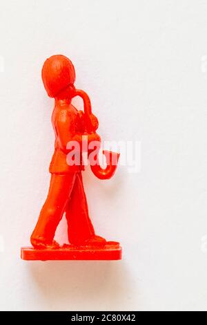 Airfix 1960 HO/00 scale figure from the Guards Band set. Toy Guardsman marching and playing the saxophone, modelled in red plastic. White background Stock Photo