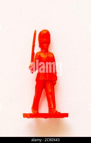 Airfix 1960 HO/00 scale figure from the Guard series. Red plastic toy Guardsman officer marching and holding a sword. White background. Stock Photo