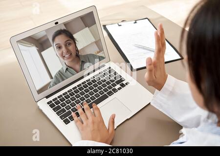 Doctor consulting indian woman patient by online video call on laptop screen. Stock Photo