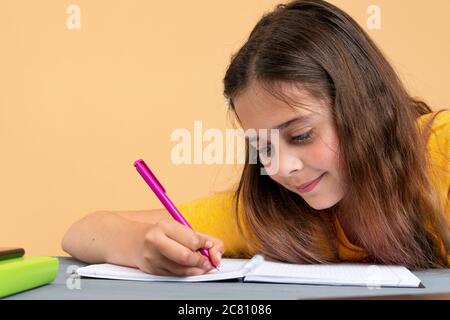 Focused european school girl studying with books preparing for test exam writing essay doing homework at home, teenage student learning assignment Stock Photo