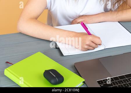 Close up of a woman hand writing in an agenda on a desk at home or office Stock Photo