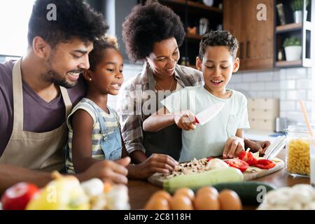 Happy family in the kitchen having fun and cooking together. Healthy food at home. Stock Photo