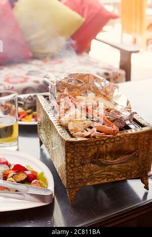 Seafood with crab, squid and shrimps on a cooper grill with drink and vegetables in cafe . Stock Photo