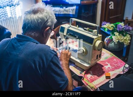 elderly man using a sewing machine Stock Photo