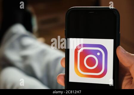 Instagram application on the smartphone in mans hand. Man laying and using application for dating and meeting. Social network concept, July 2020 Stock Photo