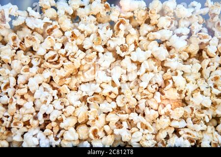 Popcorn background behind glass in a po pcorn maker. Abstract food texture. Eating for cinema Stock Photo
