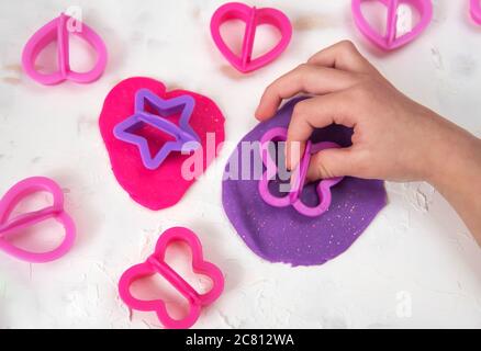 Little girl engaged in play dough modeling, top view. Stock Photo