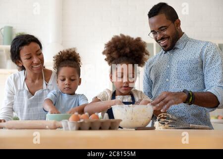Loving parents teach little children baking in kitchen Stock Photo