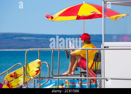 RNLI Lifeguard at Lifeguards kiosk hut on duty Bournemouth beach, Bournemouth, Dorset UK on a hot sunny day in July Stock Photo