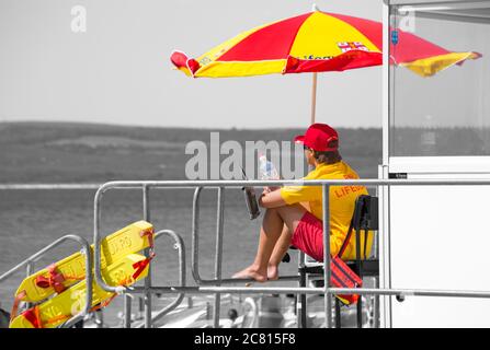 RNLI Lifeguard at Lifeguards kiosk hut on duty Bournemouth beach, Bournemouth, Dorset UK on a hot sunny day in July Stock Photo