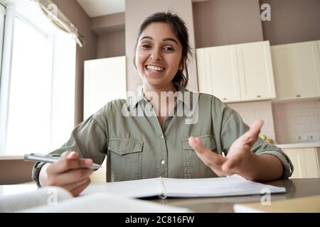 Smiling indian female teacher looking at webcam give online class by video call. Stock Photo