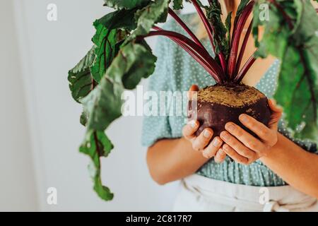 Close up of female hands holding beetroot with leaves Stock Photo