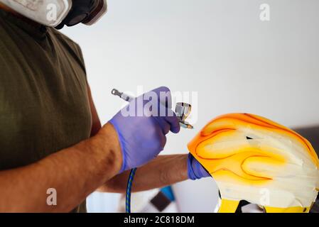 Close up of painter's hands painting flames on helmet. Stock Photo