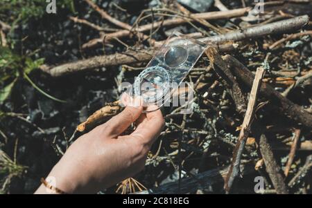 Woman uses a magnifying glass to burn a bonfire. Stock Photo