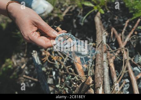 Woman uses a magnifying glass to burn a bonfire. Stock Photo
