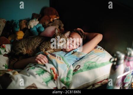 Brown tabby cat snuggles up agains the cheek of his ten year old human Stock Photo