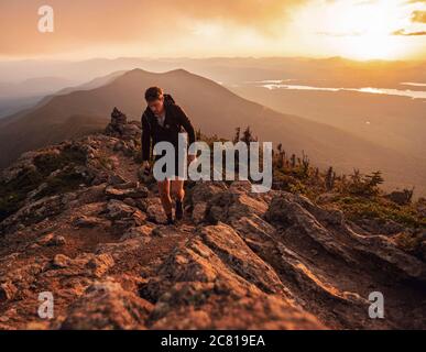Male hiker walks along Appalachian Trail on Bigelow Mountain at sunset Stock Photo