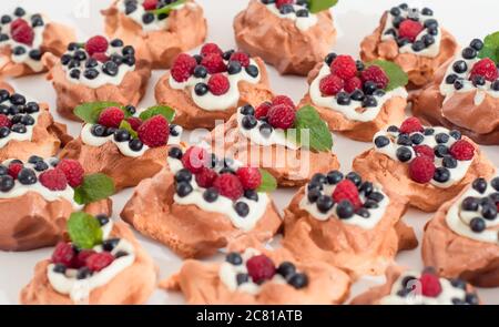 Mini Pavlova meringue nests with berries and mint on isolated on white Stock Photo