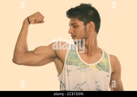Profile view of young handsome Indian man flexing his arm Stock Photo