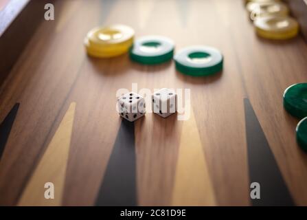 Backgammon, playing an ancient table game. Dice and chips on the backgammon board. Strategy and luck, leisure, entertainment concept. Stock Photo