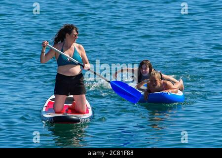West Bay, Dorset, UK.  20th July 2020.  UK Weather. Paddle boarders having fun on the water at the seaside resort of West Bay in Dorset on an afternoon of scorching hot sunshine.  Picture Credit: Graham Hunt/Alamy Live News Stock Photo