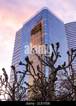 One of the many skyscrapers in the La Defence District of Paris, France, during dusk, reflecting a new skyscraper being built directly opposite it Stock Photo