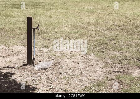 Isolated outside water tap stand pipe in farmyard baked dry by hot Summer sun. For drought in UK, water source, water shortage, hot weather, heatwave Stock Photo