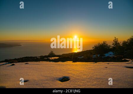last rays of light from the sunset in the mountains with snowy hills Stock Photo