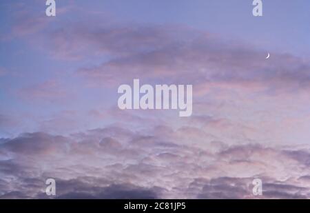 Evening purple sky with some barely visible clouds, moon crescent in right side - blue hour background Stock Photo