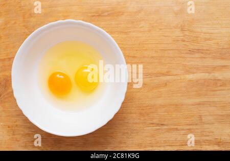 Two chicken eggs, homemade and factory, are broken in a glass plate. Difference concept of homemade natural eggs from store-bought, organic Stock Photo