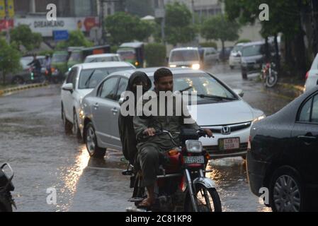 Pakistani commuters wade through a flooded street after heavy monsoon ...