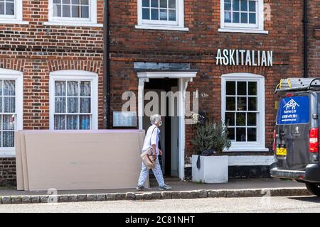20th July 2020. Old Amersham, Buckinghamshire, UK. The ASK Italian and Zizzi restaurant chain announced 2 days ago they are permanently closing 75 restaurants due to loss of income during the coronavirus covid-19 pandemic lockdown. A woman wearing a face mask walks past an ASK Italian restaurant while it is about to be boarded up. Stock Photo