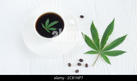 Cup of coffee with cannabis or marijuana on white wooden table Stock Photo
