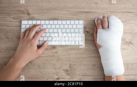 health care, work and insurance concept - top view of male hands with bandage using computer Stock Photo