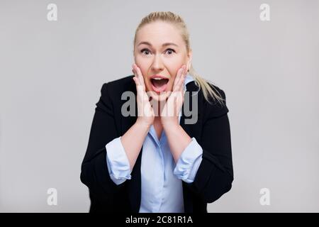 announcement or advertisement concept - surprised blonde woman screaming about something over gray background Stock Photo