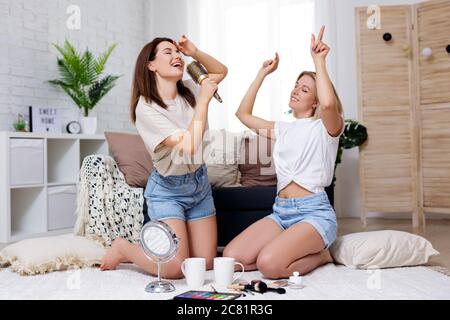 female friendship and home party concept - portrait of two beautiful girls having fun together in cozy living room Stock Photo