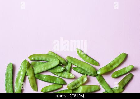 Frozen vegetables such as pea pods spread out on the button edge on a pink background with copy space. Top view. Horizontal orientation Stock Photo