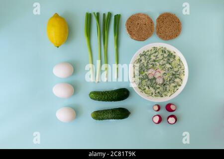 Cold soup in a deep white dish with ingredients. Okroshka, a traditional dish of Russian cuisine. Top view. Food knolling. Stock Photo
