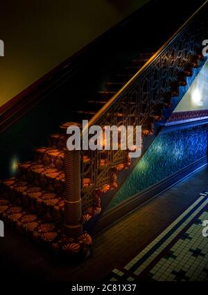 Colorful flare lighting inside old building with staircase and tin embossed wainscoting with mosaic tile floor in mysterious atmosphere, USA Stock Photo