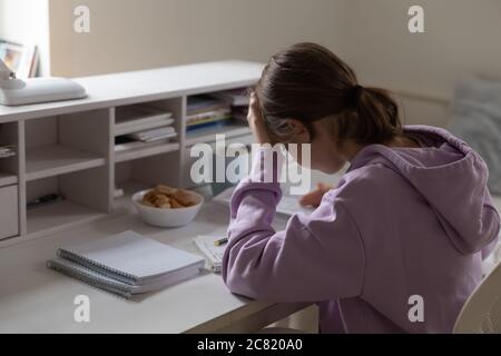 Upset tired teenage girl studying at home, touching forehead Stock Photo