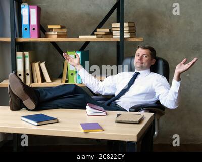 Satisfied businessman celebrates success. The man sits with his feet on the table. Stock Photo