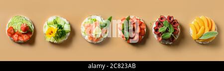 Rice cakes with different types garnish fruits, vegetables, microgreens on natural beige background. Banner. Stock Photo