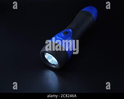 Lit black and blue LED flashlight on black background Stock Photo