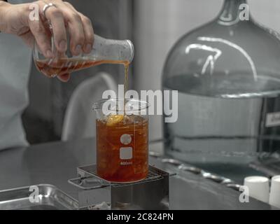 Barista hand holding Lab Borosilicate Glass Beaker Mixing tea drink beverage In Chemistry Bar Beaker Cocktail. Stock Photo