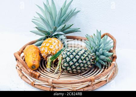 Fruit Hand-woven bamboo basket with a pineapple, Papaya fruits isolated on white background Stock Photo